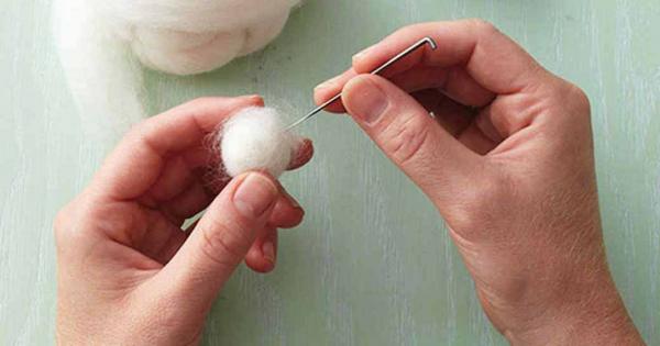 two hands needled felting a small off white core wool ball