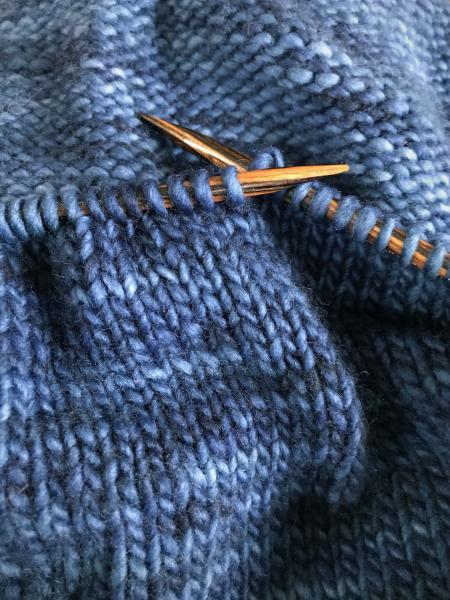 knitting needles with yarn on grey and golden yellow projects
